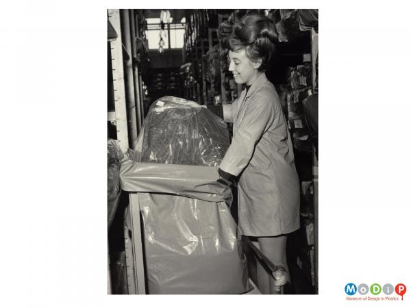 Scanned image showing a female worker filling a plastic transit sack.