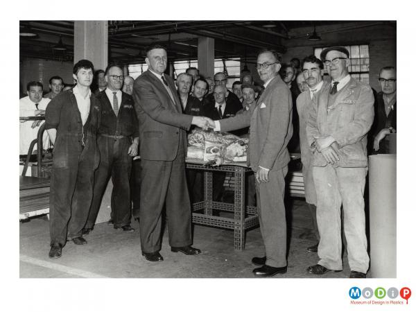 Scanned image showing a male employee receiving a gift.