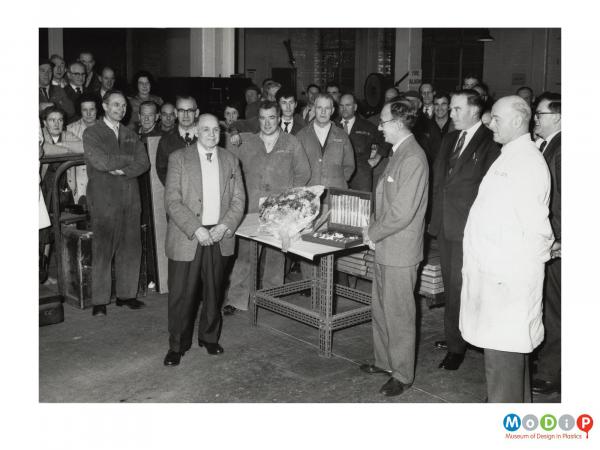 Scanned image showing a male employee receiving a gift.
