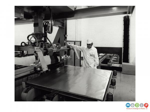 Scanned image showing a male worker at a sheet production machine.