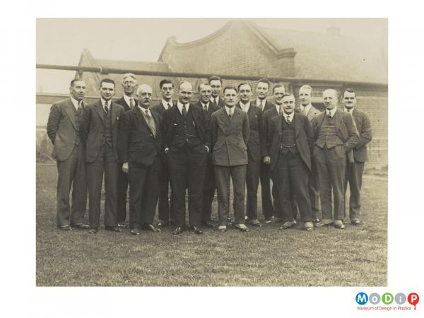 Scanned image showing a standing group of men in suits.