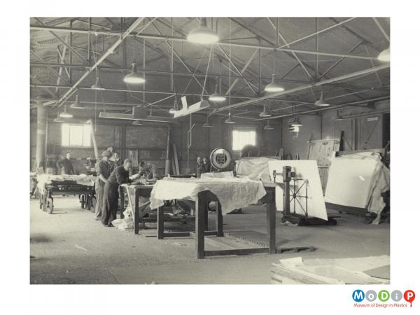 Scanned image showing workers inside a factory room with weighing machinery.