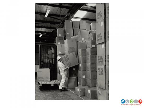 Scanned image showing a man stacking boxes.