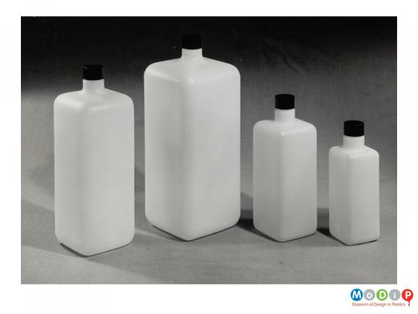 Scanned image showing a group of 4 differently sized square bottles.