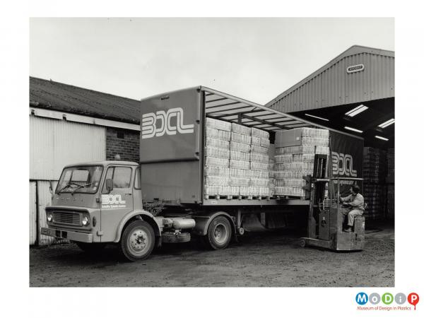 Scanned image showing pallets being loaded on to a lorry.