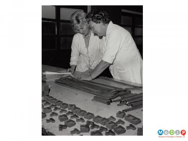 Scanned image showing two female workers assembling gaskets from Plastazote sections.