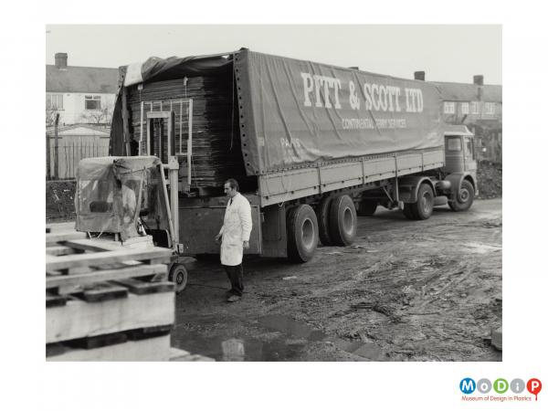 Scanned image showing sheets of material being forklifted into the back of a lorry.