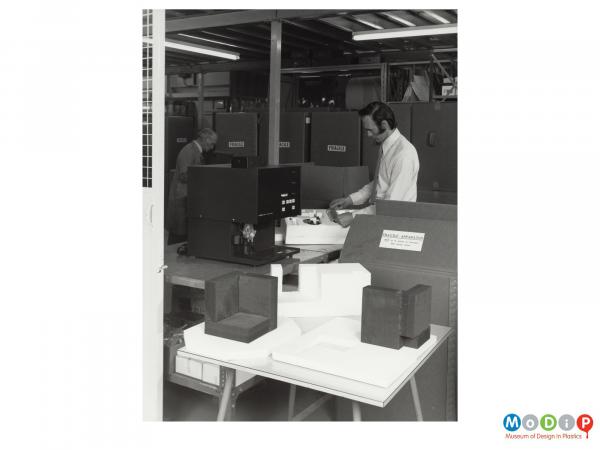 Scanned image showing a male worker packaging equipment.