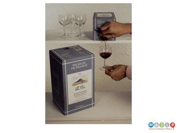 Scanned image showingWine being poured from a tap in a box.