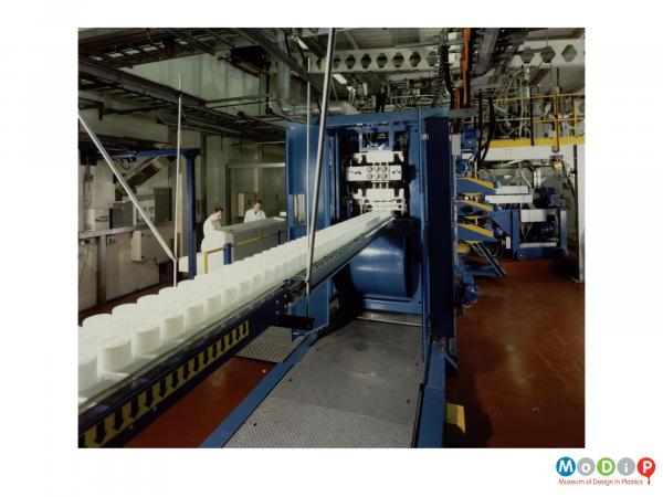 Scanned image showing a machine producing food containers.