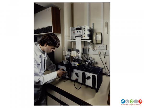 Scanned image showing a man in a lab coat operating a measuring device.