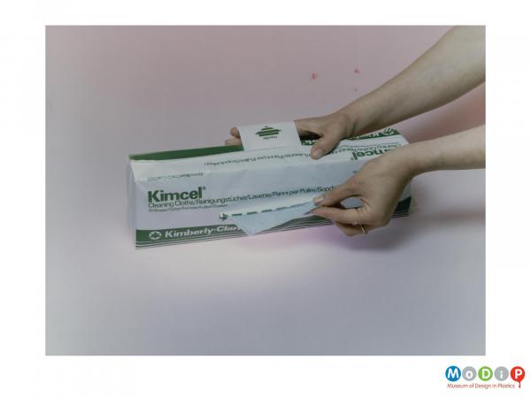 Scanned image showing a packet of cleaning cloths demonstrated by a pair of women's hands.