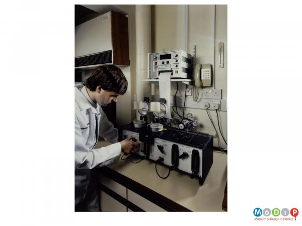 Scanned image showing a male lab technician operating testing equipment.