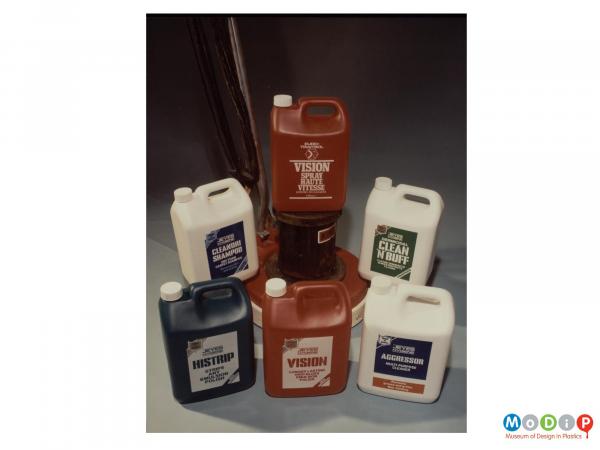 Scanned image showing a range of 6 cleaning product bottles arranged around a floor polisher.
