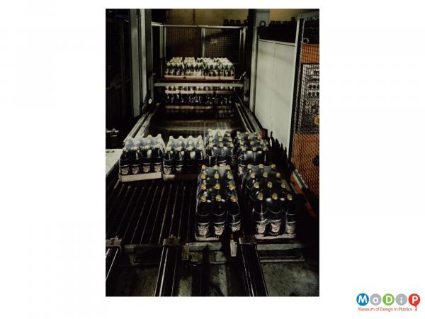 Scanned image showing shrink wrapped packs of bottles on a packing machine.