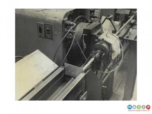 Scanned image showing cable running through an extruding machine.