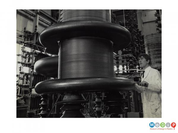 Scanned image showing male worker stood at a high voltage induction coil.