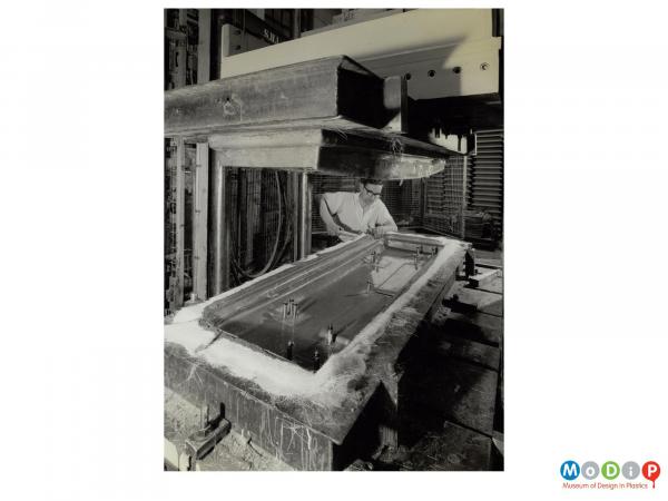 Scanned image showing a male worker beginning to remove a panel from a mould.