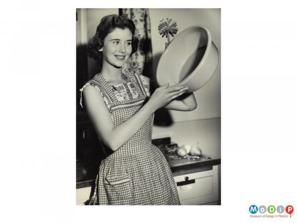 Scanned image showing a female model holding up a washing up bowl.