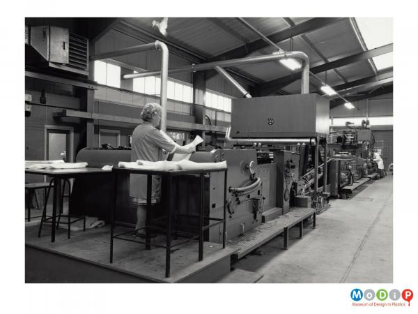 Scanned image showing a female worker at the end of a sack production line.