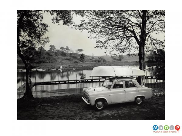 Scanned image showing a small sailing boat on the roof of a car.