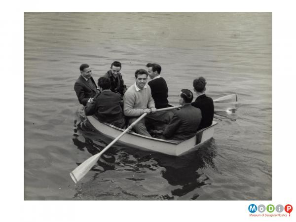 Scanned image showing a rowing boat with 7 men in it.