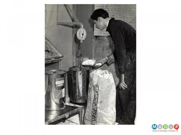 Scanned image showing a man weighing filler.
