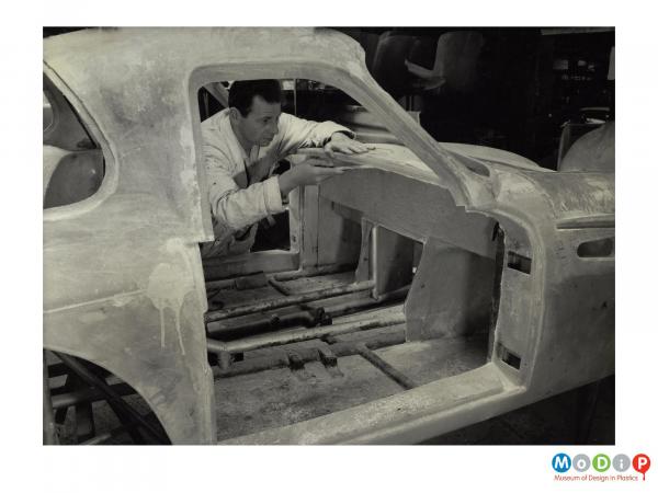 Scanned image showing a sports car being built.