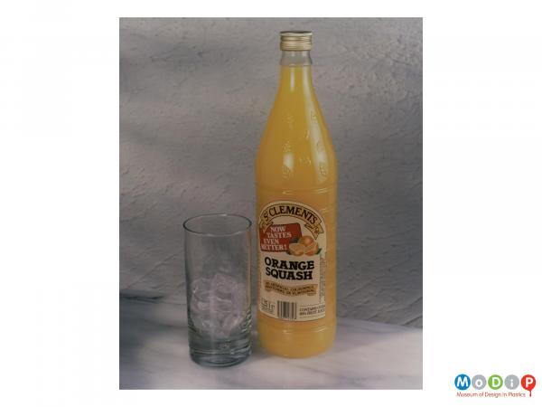 Scanned image showing an orange squash bottle next to an ice filled glass.