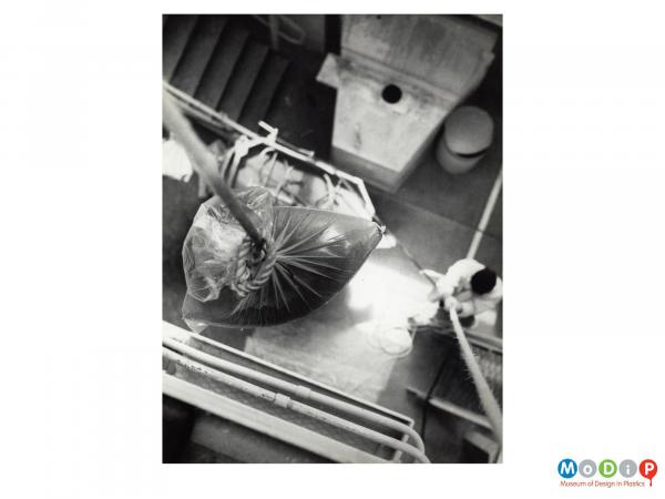 Scanned image showing a polythene bag held high ready for a drop test.