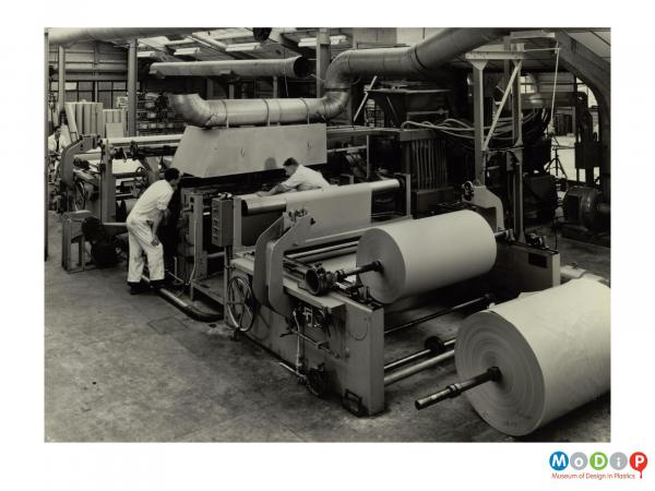 Scanned image showing large rolls of paper being coated with plastics.