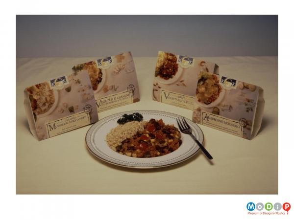 Scanned image showing 4 ready meal boxes behind a meal arranged on a plate.