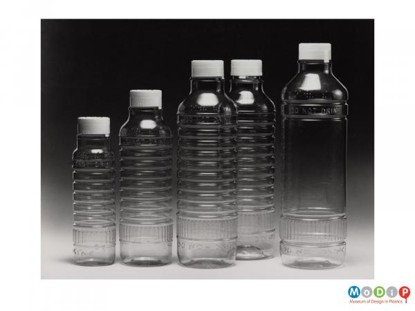 Scanned image showing 5 clear bottles designed to contain chemical based products.
