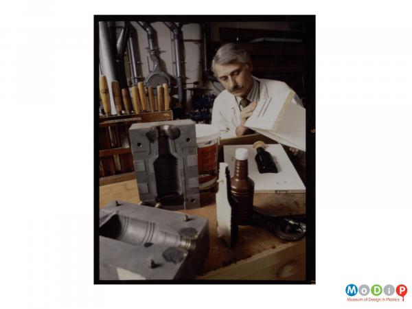 Scanned image showing a male worker creating moulds for a bottle.