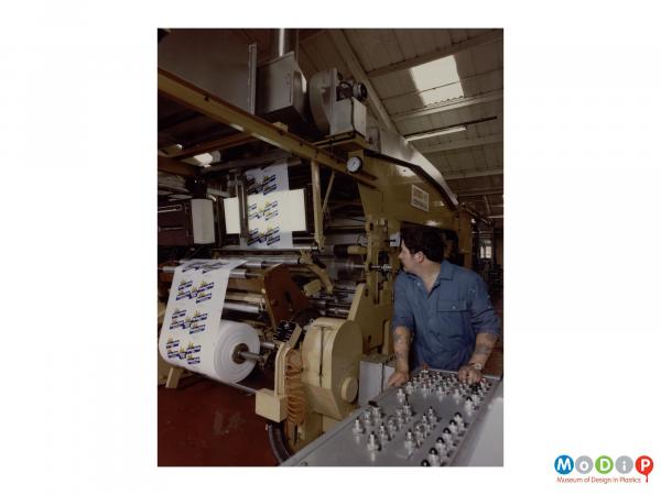 Scanned image showing a amle worker operating machinery producing the material from which bread bags are produced.