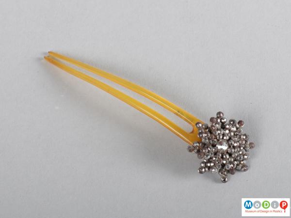 Top view of a hairpin showing the flower embellishment and two teeth.