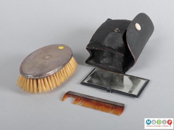 Top view of a grooming set showing the brush, comb, mirror and pouch.