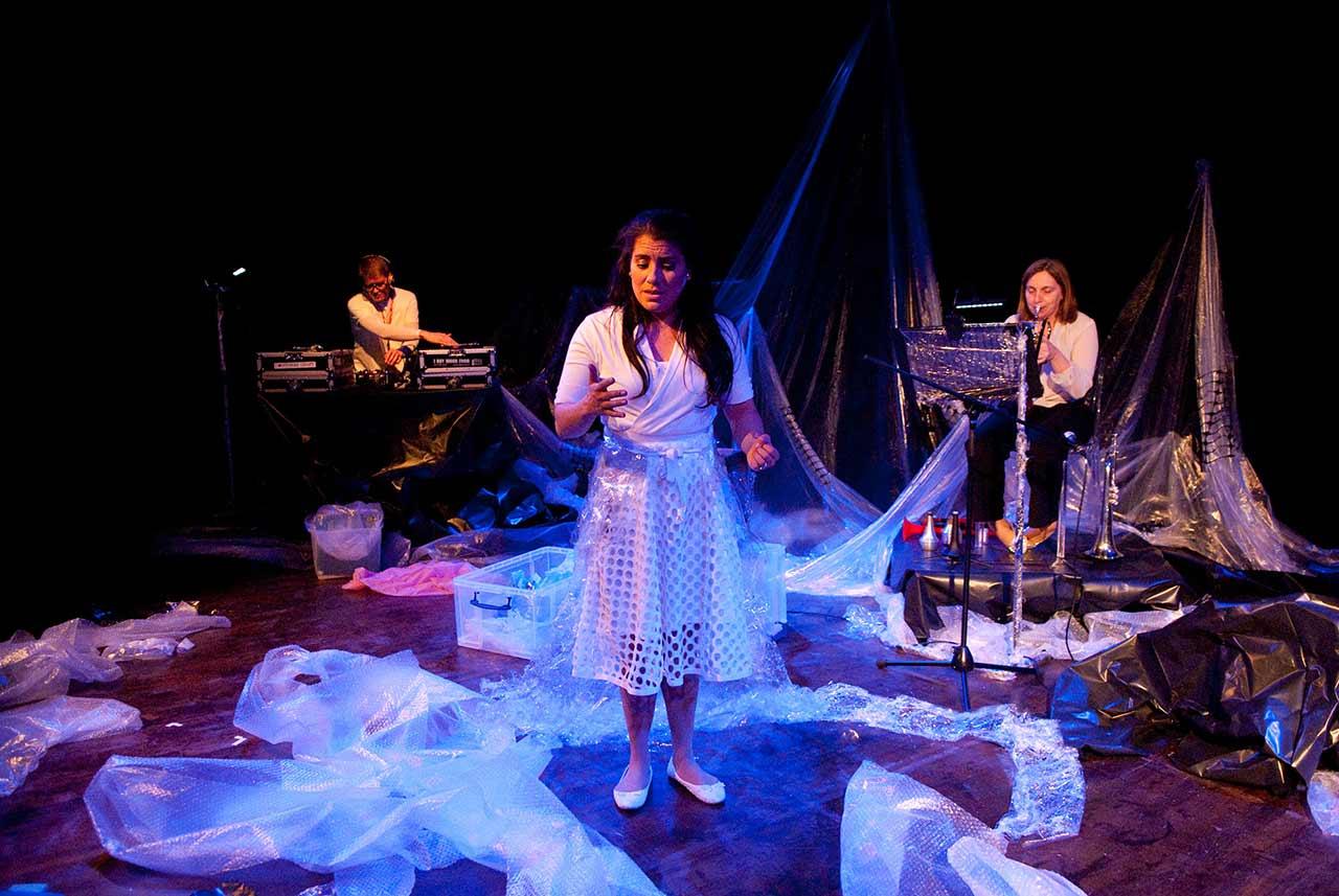 A stage set with the three cast members surrounded by bubble wrap.