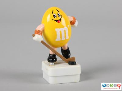 Front view of a yellow M&M figure showing the smiling face and the limbs.