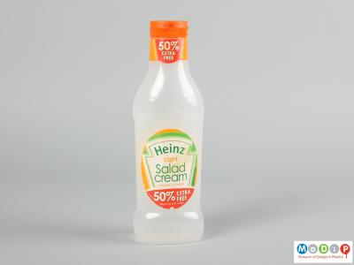Front view of a salad cream bottle showing the orange cap and translucent body.