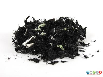 Side view of a pile of shredded flakes showing the mainly black pieces.