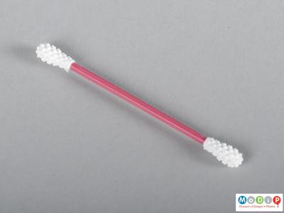 Side view of a reusable ear cleaner showing the pink shaft and textured tips.